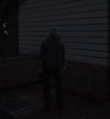 a man wearing a hat stands in front of a brick wall