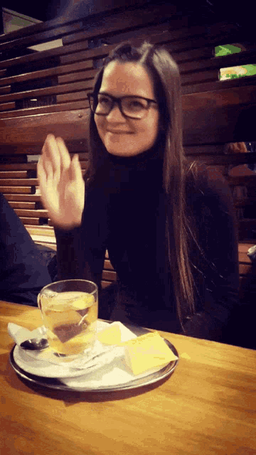 a woman wearing glasses is sitting at a table with a cup of tea