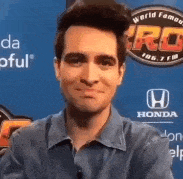 a man in a blue shirt is smiling in front of a sign that says honda .