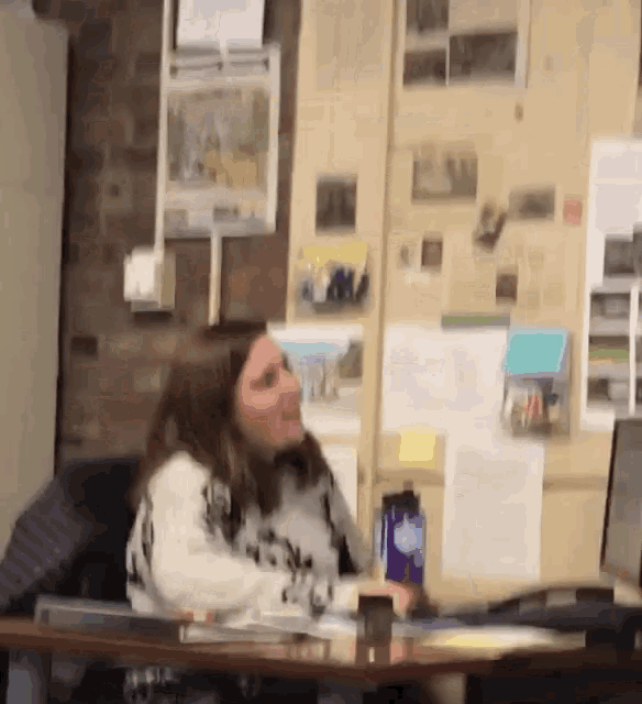 a woman is sitting at a desk with a bottle of water