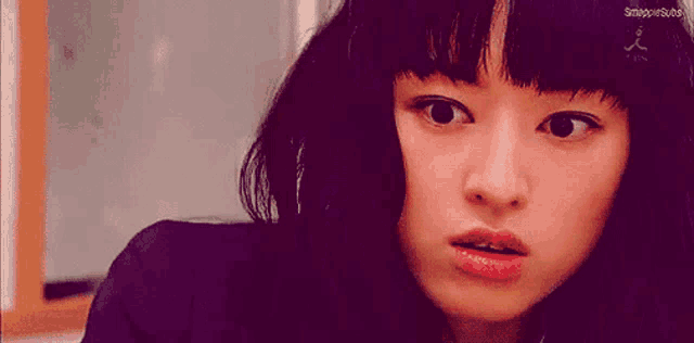 a close up of a woman 's face with a serious look on her face