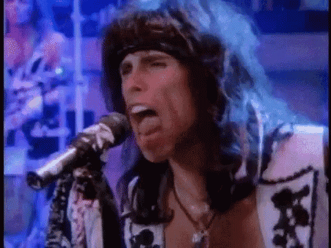 a close up of a man singing into a microphone with his tongue out .