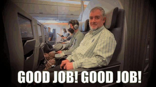 a man in a plaid shirt sits in an airplane seat with the words " good job good job " above him