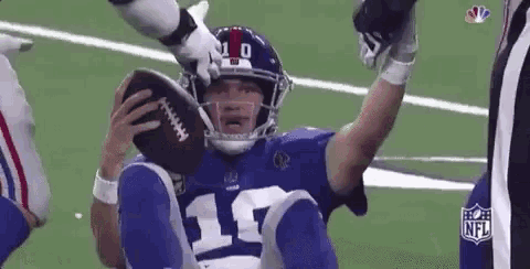 a football player is sitting on the ground holding a football in his hand .