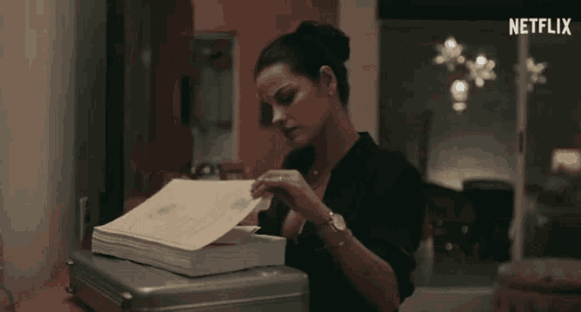 a woman is looking at a stack of papers with the netflix logo in the corner