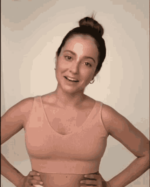 a woman with her hands on her hips is wearing a pink crop top