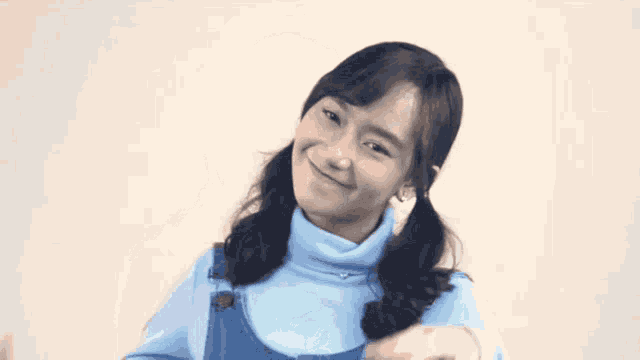 a girl with pigtails is wearing a blue sweater