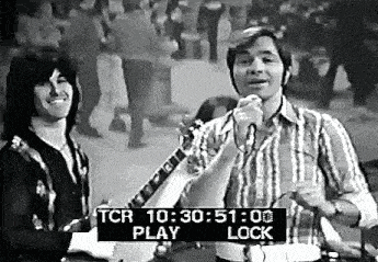 a man is singing into a microphone while another man plays a guitar .