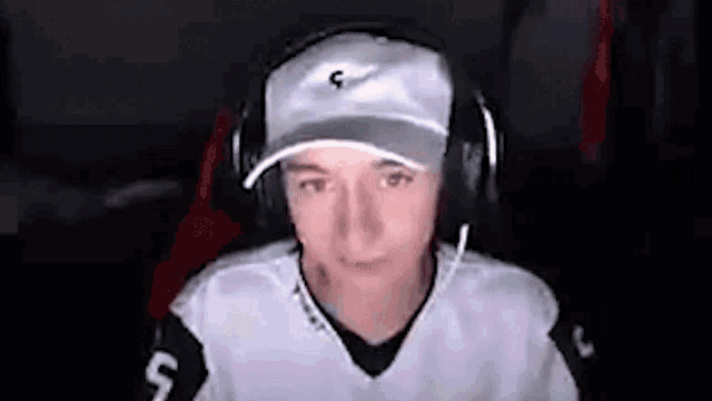 a young man wearing a hat and headphones is sitting in front of a computer screen .
