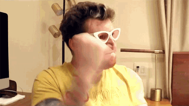 a man wearing sunglasses and a yellow shirt that says sunday on it