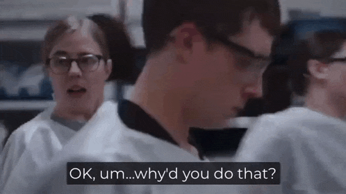 a man wearing glasses and a lab coat is talking to a woman in a laboratory .