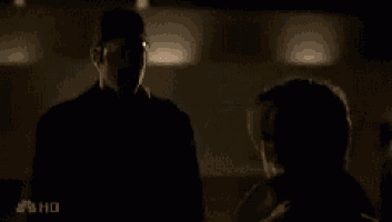 a man and a woman are standing in a dark room and talking to each other .