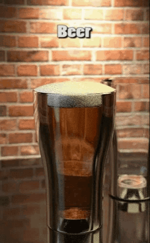 a glass of beer in front of a brick wall with the word beer on it