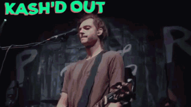 a man singing into a microphone with the words kash 'd out above him .