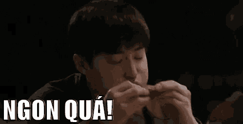 a young man is eating a hamburger with chopsticks while sitting at a table .