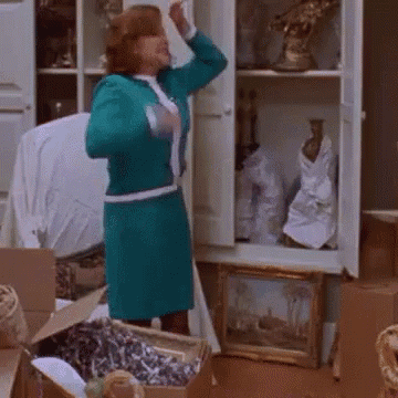 a woman in a blue dress is standing in front of a cabinet filled with vases and paintings ..