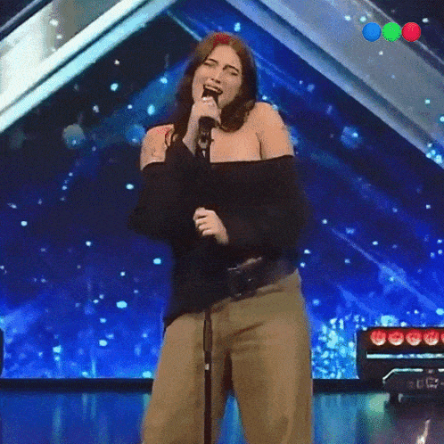 a woman singing into a microphone with a blue background