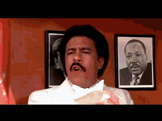 a man with a mustache is standing in front of a framed picture of martin luther king jr.