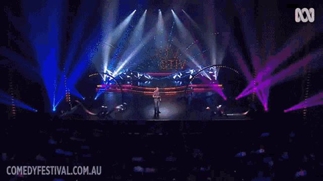 a man stands on a stage with the words comedy festivals.com.au on the bottom