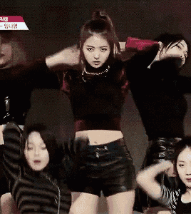 a group of women are dancing on a stage and one of them is wearing a crop top .