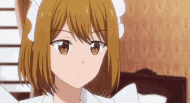 a girl with short brown hair is wearing a white apron and looking at the camera .