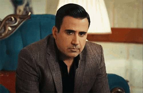 a man in a suit sits on a blue chair