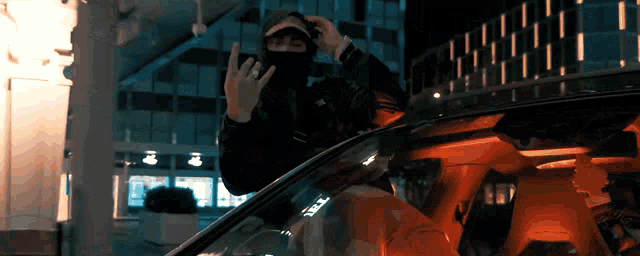 a man in a mask is sitting in a car and giving the middle finger