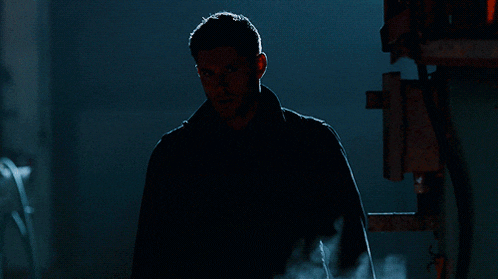 a man in a dark room with smoke coming out of the corner