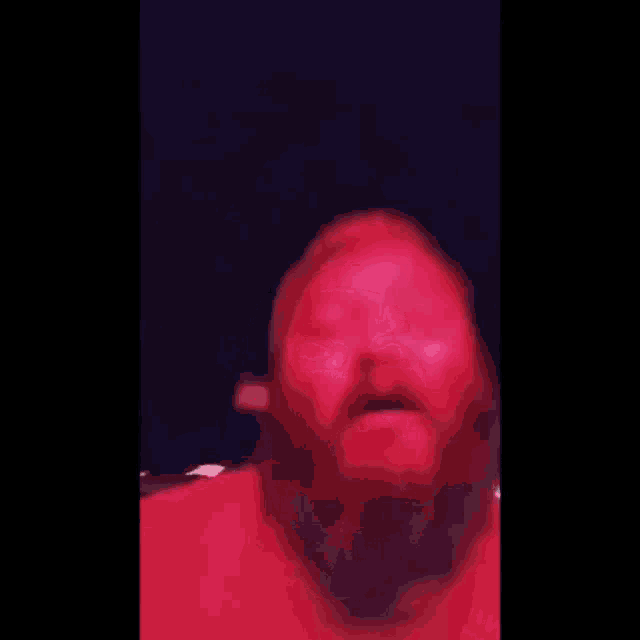 a close up of a man 's face with a red light behind him