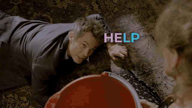a man is laying on the floor with help me written on the carpet