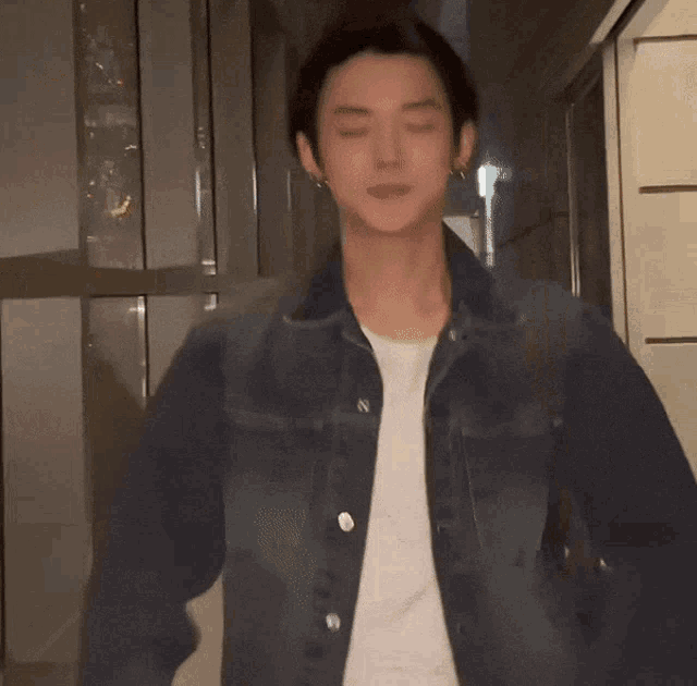 a man wearing a denim jacket and a white t-shirt with the letter n on it