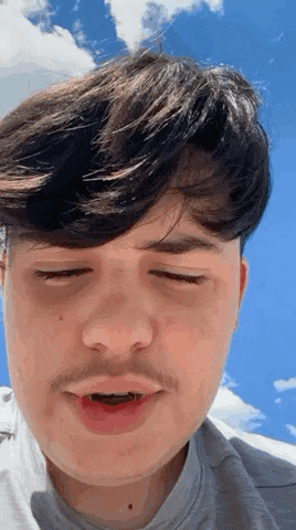 a young man with a mustache is making a funny face with his eyes closed and his mouth open .
