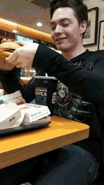 a man sitting at a table with a cup that says ' вкуса ' on it