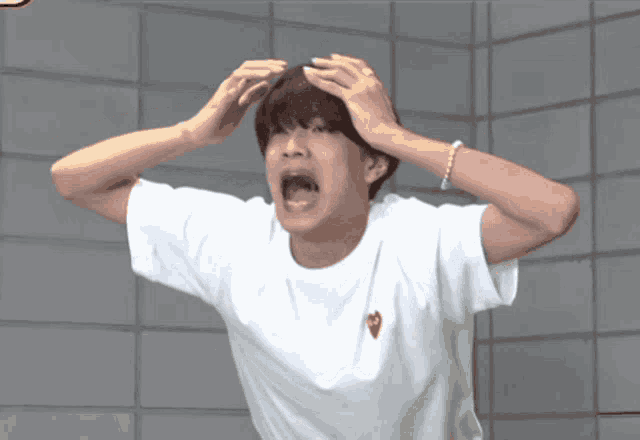a man wearing a white shirt with a heart on it is making a funny face