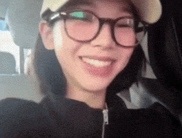 a woman wearing glasses and a baseball cap is smiling