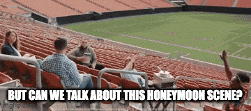 a group of people are sitting in the stands of a stadium with the words but can we talk about this honeymoon scene .