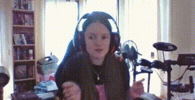 a girl wearing headphones is sitting in front of a drum set in a room .
