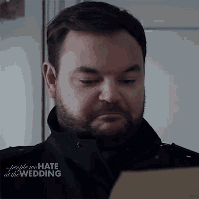 a man with a beard is looking at a laptop screen with the words people we hate at the wedding