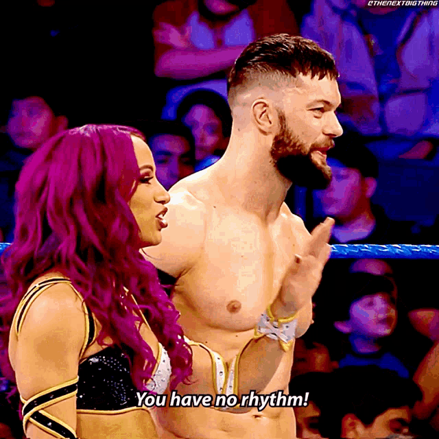 a man and a woman in a wrestling ring with the woman saying you have no rhythm
