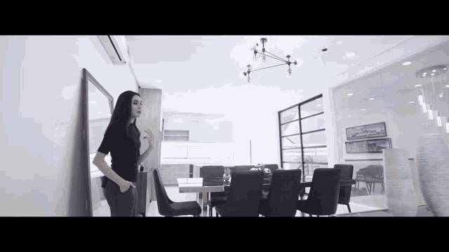 a woman is standing in a dining room with a table and chairs