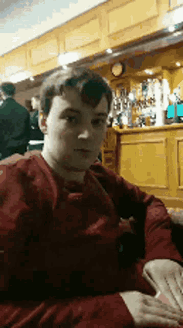 a man in a red sweater is sitting in a bar