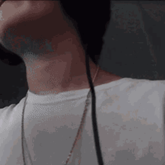a man wearing headphones and a necklace looks down at something