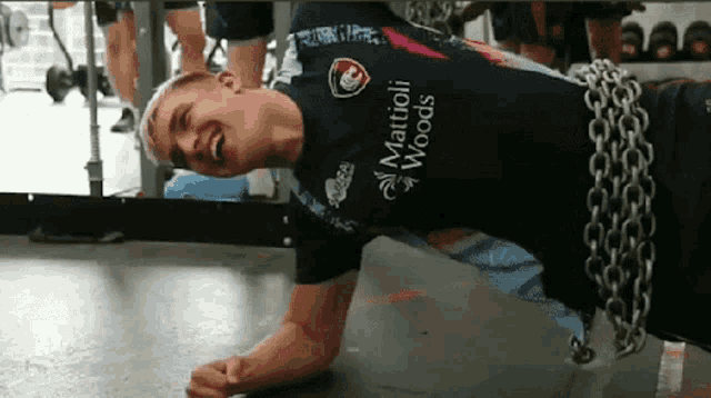 a man in a martioli woods shirt is doing push ups