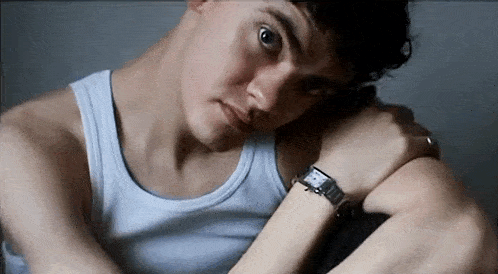 a man wearing a white tank top and a watch on his wrist