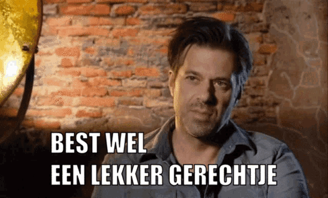 a man stands in front of a brick wall with the words best wel een lekker gerechtje below him