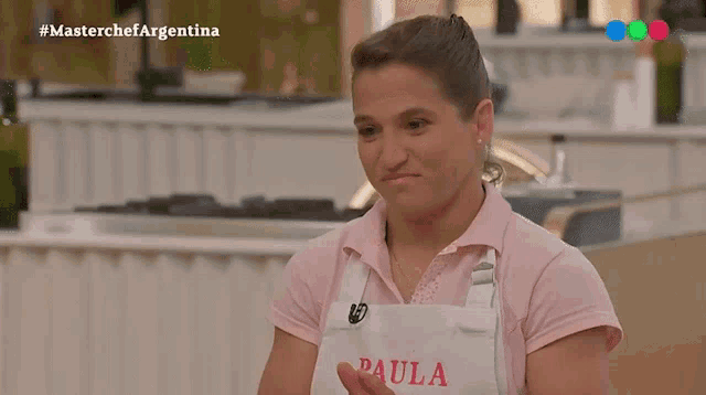 a woman wearing a pink shirt and white apron with paula written on it