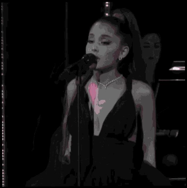 a woman singing into a microphone with a pink broken heart in front of her