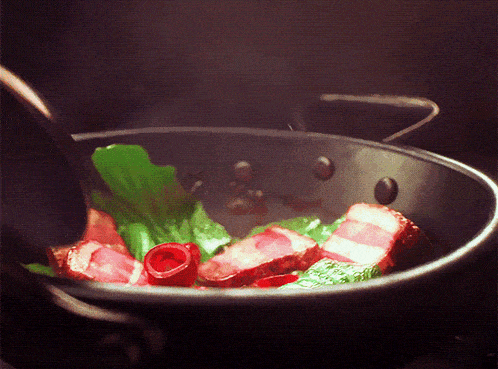a pan filled with meat and vegetables is being stirred with a spoon