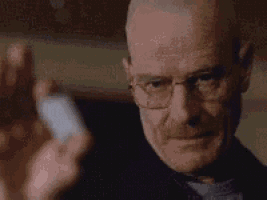a close up of a man wearing glasses holding a bottle of pills .