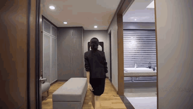 a woman in a black skirt is walking through a hallway leading to a bathroom